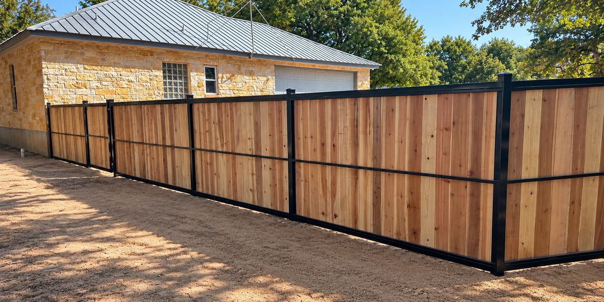 New cedar privacy fence with black steel frame beside a stone house