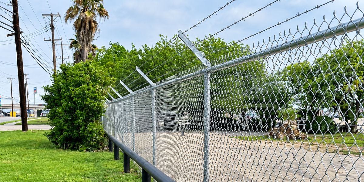 Galvanized chain link security fence with barbed wire top and bollard rail